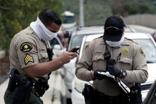 4月11日,在美国加利福尼亚州圣迭戈,警察佩戴"口罩"在街边检查车辆
