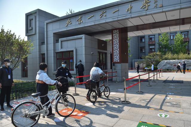 4月27日,北京一六一中学的学生推着自行车有序进入学校