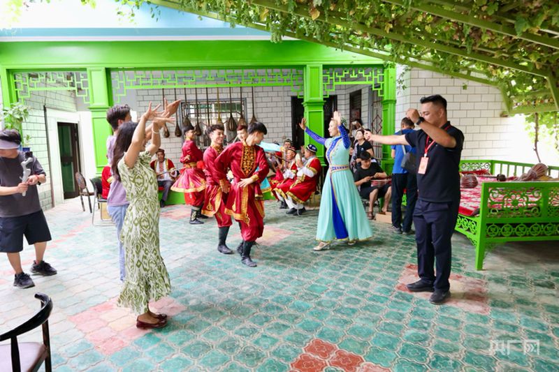 在努尔东·司马义的院落里,艺人与游客即兴共舞(央广网记者 梁瑜琳 摄)