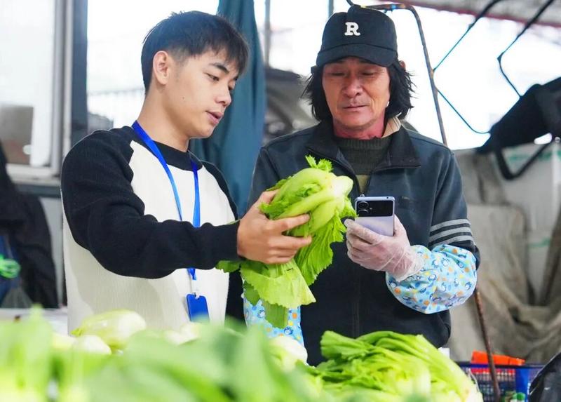 工作人员正核对菜价。海口市融媒体中心记者 杨忠凯 摄 农贸市场工作人员正与摊主核对今日菜价。__本报记者 杨忠凯 摄.jpg