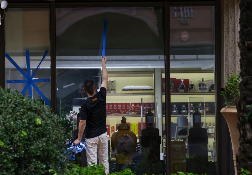 9月24日,随着今年第18号台风“桦加沙”强度逐渐减弱并远离深圳,在深圳南山区一家刚开门的临街店铺,一名工作人员拆掉玻璃上的胶带。新华社记者 毛思倩 摄