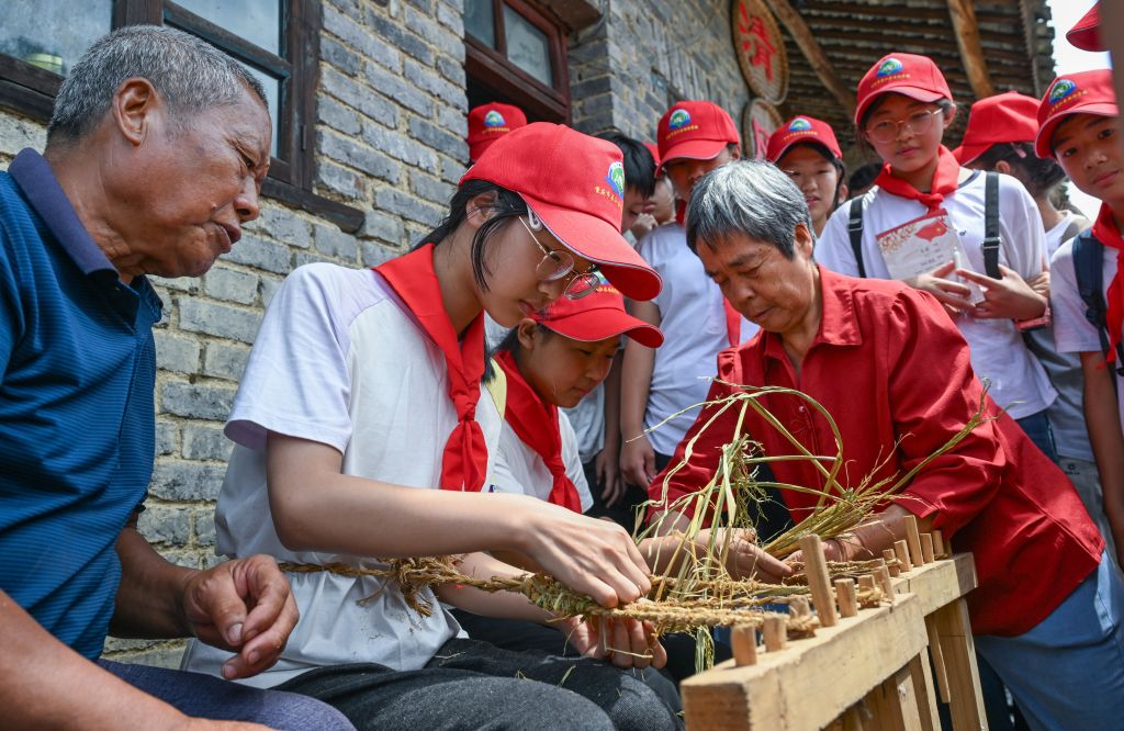 9月3日,重庆市綦江区安稳学校的学生参加“綦迹少年·重走长征路”活动,在村民指导下体验编草鞋。新华社记者陈诚 摄