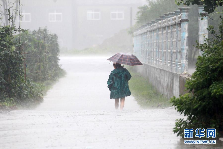 7月5日,在江苏省淮安市洪泽区,行人在雨中涉水前行.