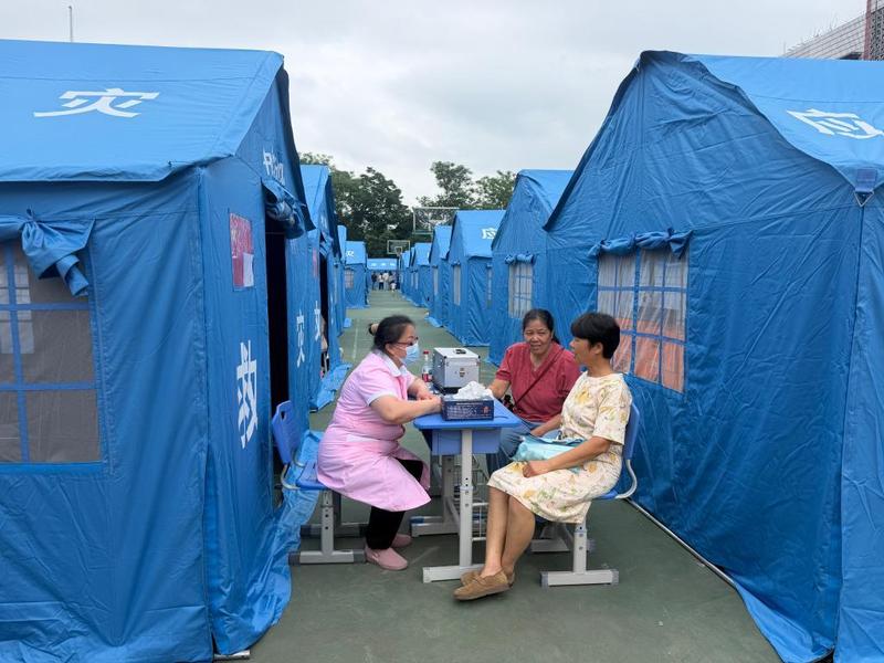 在太阳村中心校安置点,医护人员与居民沟通健康情况。新华社记者 农冠斌 摄