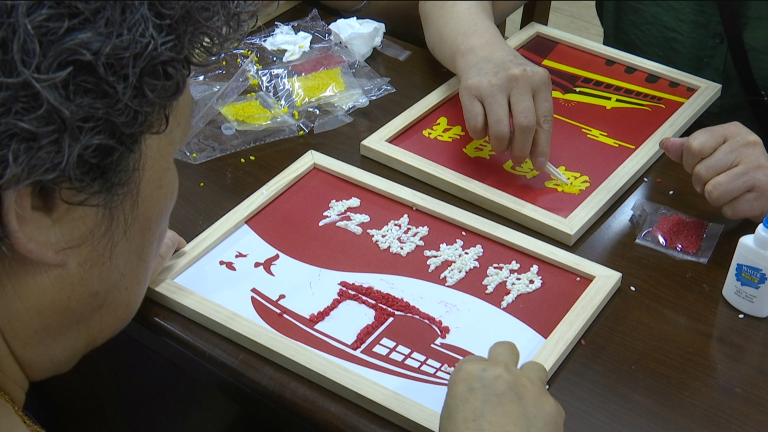 杂粮认真地在竹匾上创作红船,党旗,天安门,中国地图等美丽的五谷画